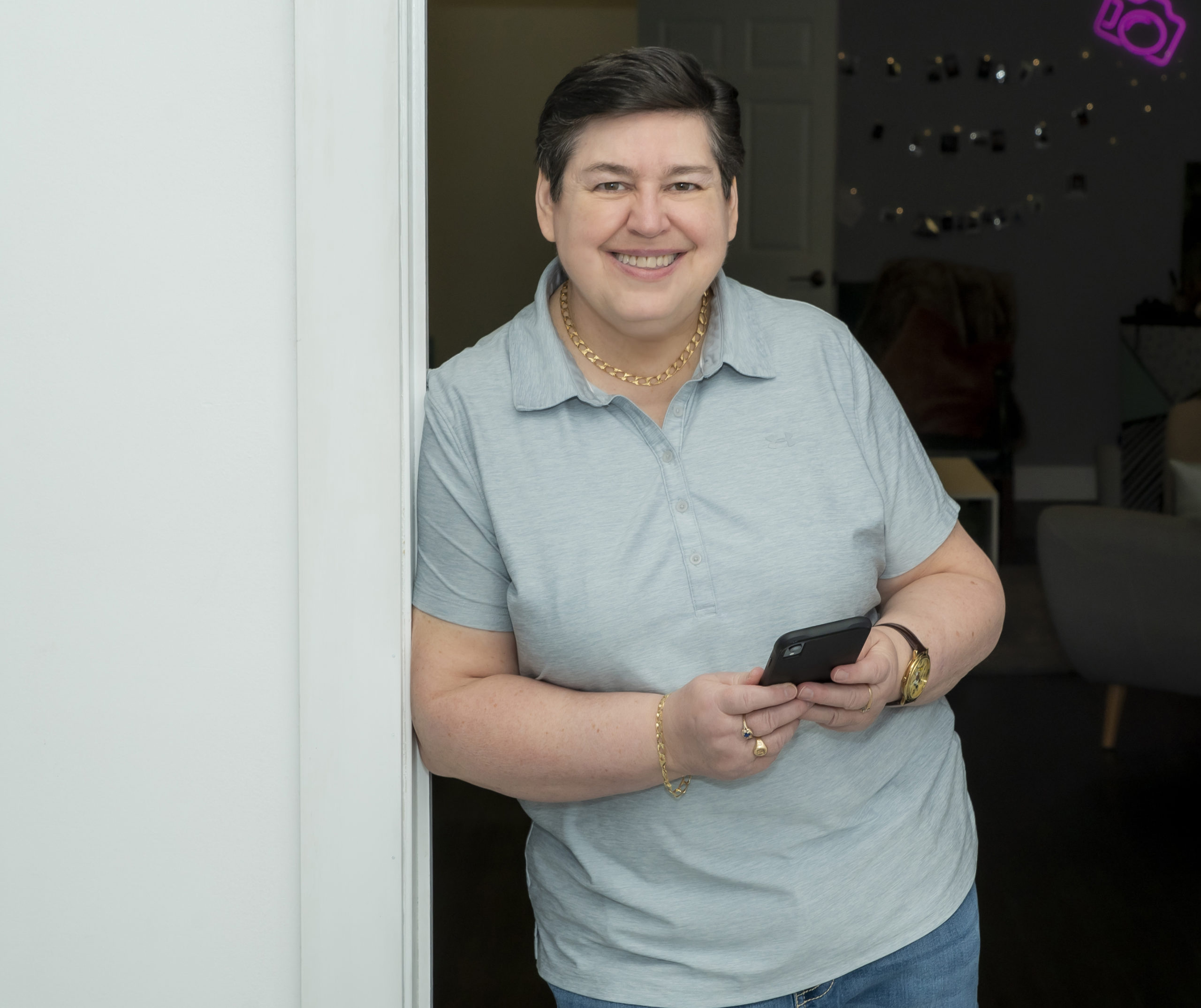 NB Realtor Darlene Smith leaning against a doorframe with phone in hand